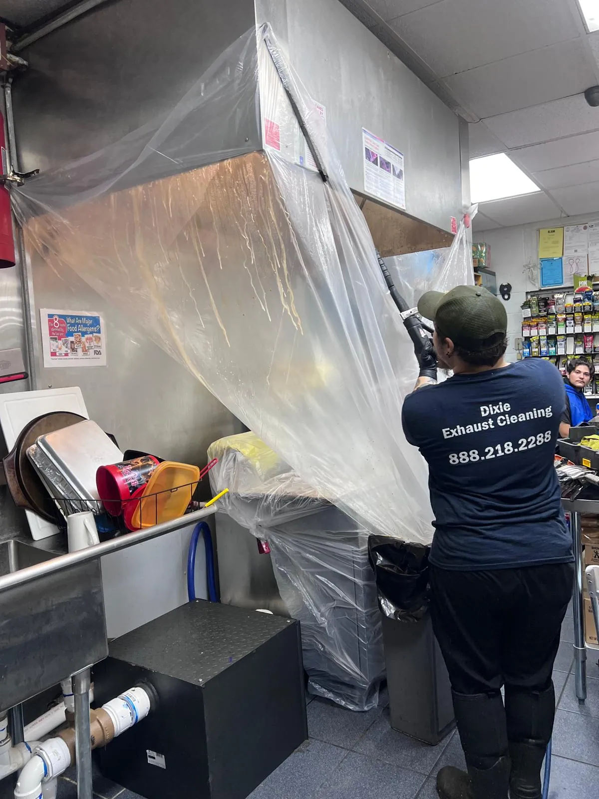 A Dixie Exhaust Alabama crew member cleaning a commercial kitchen hood