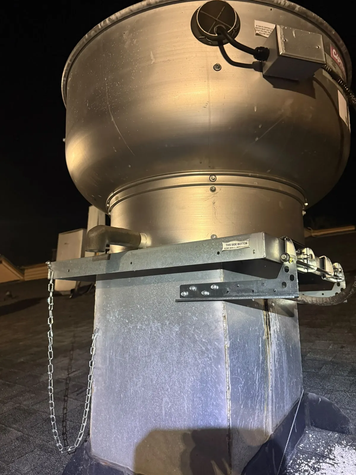 Installed roof-accessory hinge beside commercial rooftop exhaust equipment